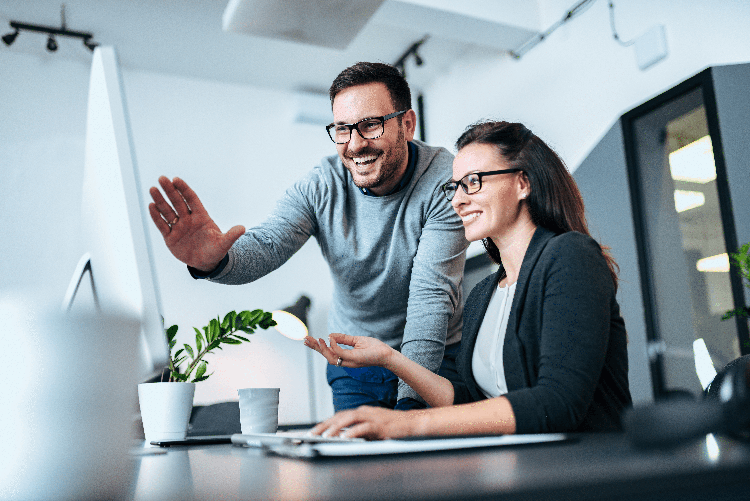 Man and woman review computer monitor