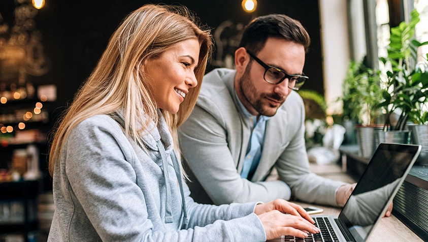 Two People Discussing Information on a Laptop - Micro Accounting