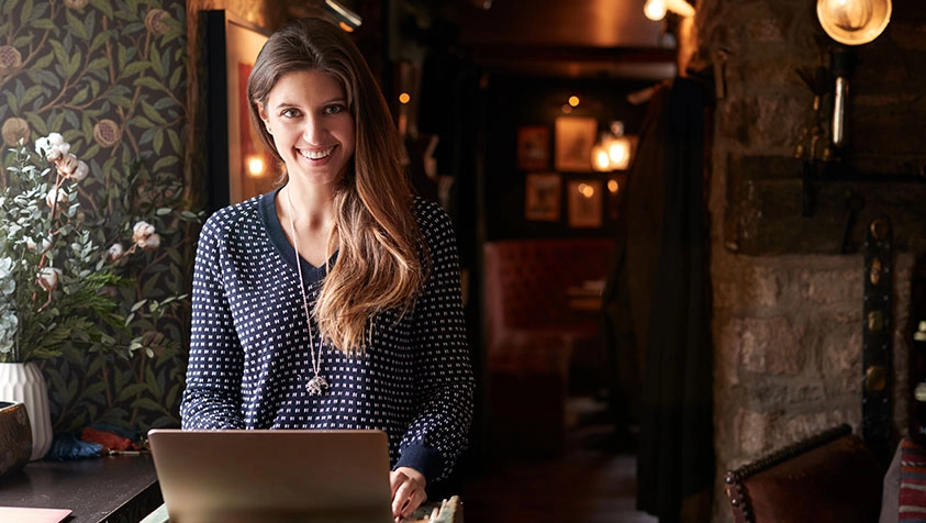 Hospitality Employee Greeting Customers with a Laptop | MicroAccounting